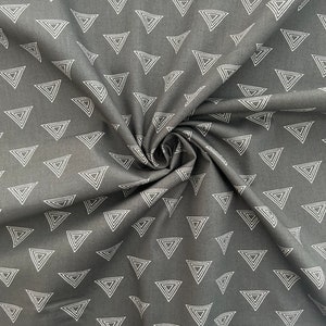 Puede incluir: Tela negra con un patr&oacute;n geom&eacute;trico blanco de tri&aacute;ngulos conc&eacute;ntricos repetidos.