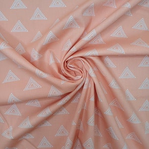 Puede incluir: Tela de color melocot&oacute;n con un patr&oacute;n geom&eacute;trico blanco de tri&aacute;ngulos repetidos. La tela est&aacute; doblada y drapeada, mostrando la textura y el patr&oacute;n.