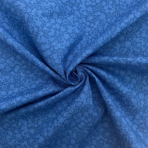 Pu&ograve; includere: Un primo piano di un tessuto blu con un motivo floreale bianco. Il tessuto &egrave; morbido e ha una lucentezza sottile.