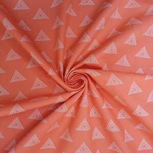Puede incluir: Tela coral con un patr&oacute;n geom&eacute;trico blanco de tri&aacute;ngulos repetidos. La tela est&aacute; doblada y tiene una textura suave y lisa.