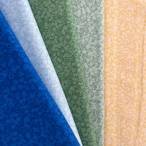 Könnte beinhalten: Vier Stoffmuster mit einem weißen Blumenmuster auf verschiedenen farbigen Hintergründen. Die Muster sind blau, grün, hellblau und gelb.