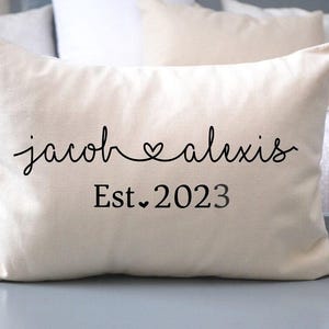 May include: A white pillow with black text that reads "jacob &hearts; alexis Est. 2023".