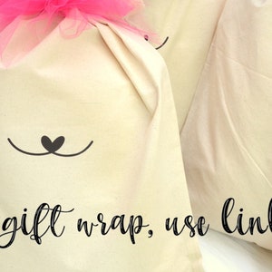 May include: Four white fabric gift bags with a cute black cat face design. Each bag has a drawstring closure and is decorated with a tulle bow in pink, blue, or white. The text "To add gift wrap, use link below!" is written in black cursive at the bottom of the image.