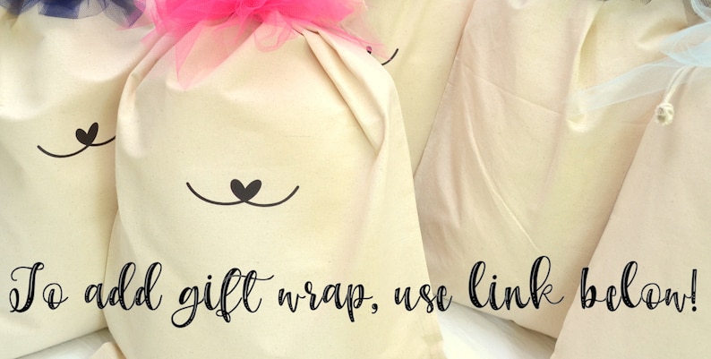 May include: Four white fabric gift bags with a cute black cat face design. Each bag has a drawstring closure and is decorated with a tulle bow in pink, blue, or white. The text "To add gift wrap, use link below!" is written in black cursive at the bottom of the image.