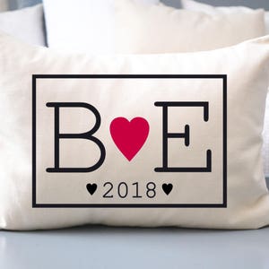 May include: White pillow with black lettering that says "B ♥ E 2018" inside a black rectangle.