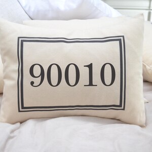May include: A white pillow with a black border around a black rectangle containing the number 90010.
