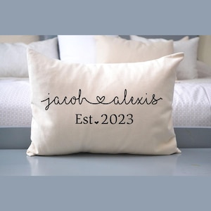 May include: White throw pillow with black text that reads "jacob ♥ alexis Est. 2023".