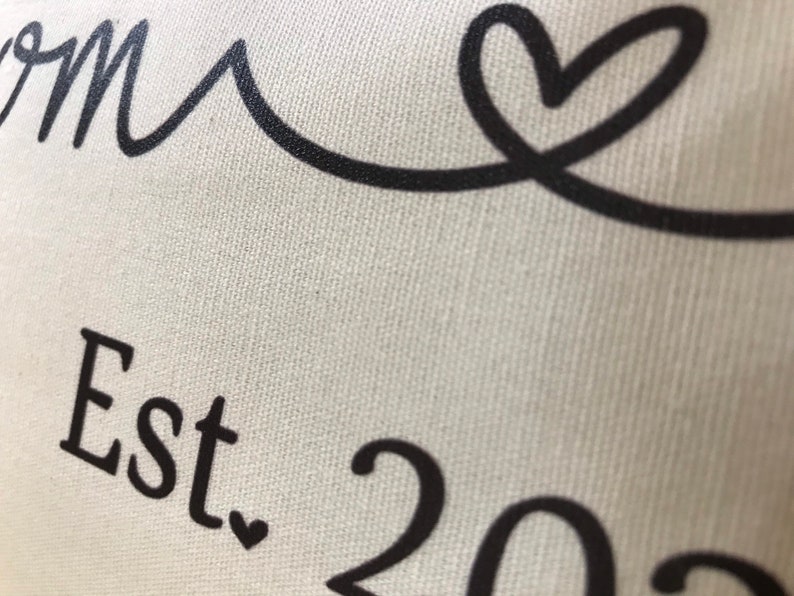 May include: White canvas pillow with black text that reads "Home Est. 202" and a black heart.