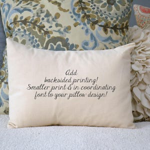 May include: A white pillow with the text "Add backsided printing! Smaller print & in coordinating font to your pillow design!" printed on it. The pillow is sitting on a white surface with other pillows behind it.