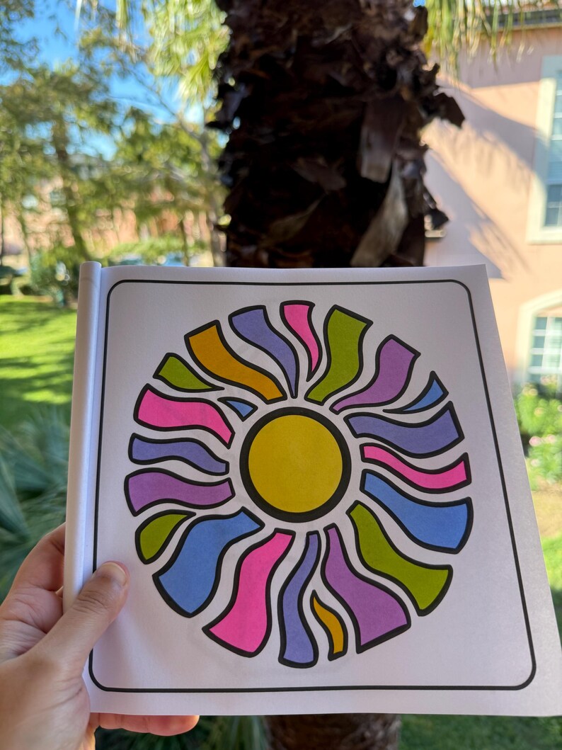 May include: A coloring book page with a colorful sun design. The sun is surrounded by a circle of wavy lines in shades of pink, purple, blue, green, and yellow.