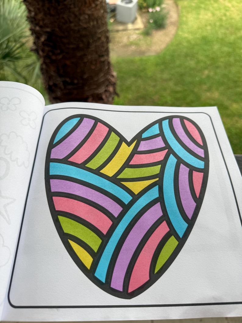 May include: A coloring book page featuring a large heart shape with a colorful geometric pattern. The heart is outlined in black and filled with pink, purple, blue, green, and yellow stripes.