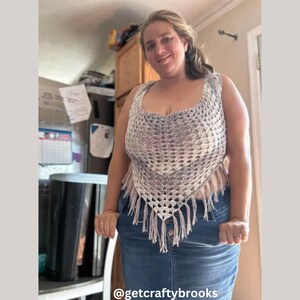 May include: A handmade crochet top in shades of gray and white, featuring a unique open weave design. The top has a fringed bottom and a scoop neckline. The Instagram handle @getcraftybrooks is visible at the bottom of the image.