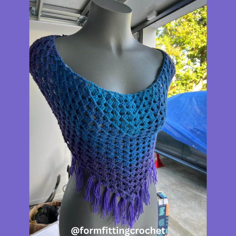 May include: A handmade crochet top in shades of blue and purple, displayed on a mannequin. The top features a scoop neck, open weave design, and fringe along the bottom edge. The text "@formfittingcrochet" is visible at the bottom.