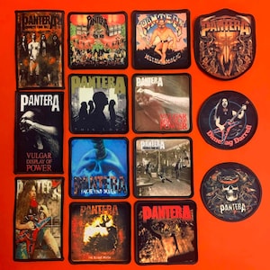 Könnte beinhalten: Eine Sammlung von zwölf Stoffaufnähern mit verschiedenen Pantera-Bandmotiven, darunter Albumcover wie Vulgar Display of Power, Far Beyond Driven und Metal Magic sowie Porträts von Dimebag Darrell, alle mit schwarzen Rändern versehen.