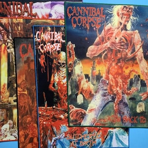 Op de afbeelding: Een verzameling Cannibal Corpse patches met verschillende albumhoezen. De patches tonen gruwelijke beelden van zombies en geweld, met de bandnaam in een druipend lettertype. Het kleurenpalet omvat rood, groen en blauw.