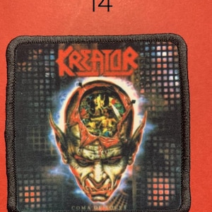 Peut inclure: &Eacute;cusson carr&eacute; avec le mot "KREATOR" en rouge, au-dessus d'une illustration d&eacute;taill&eacute;e d'un visage d&eacute;moniaque avec de la mati&egrave;re c&eacute;r&eacute;brale expos&eacute;e. L'&eacute;cusson a une bordure noire et est pos&eacute; sur un fond rouge. Le chiffre "14" est au-dessus de l'&eacute;cusson.