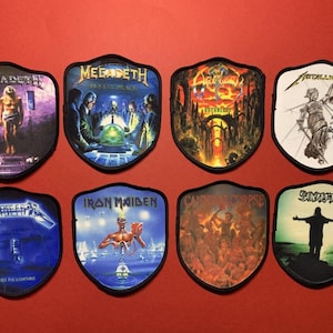 Puede incluir: Ocho parches en forma de escudo con logotipos de bandas de heavy metal, incluyendo Megadeth y Metallica. Cada parche tiene un borde negro y obras de arte coloridas que representan portadas de álbumes y nombres de bandas.