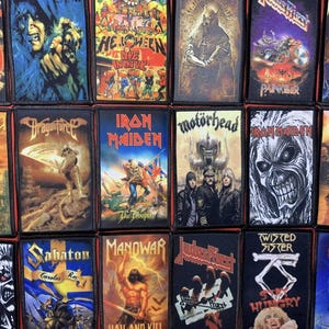 May include: A selection of rectangular patches showcasing album artwork from heavy metal bands. The patches feature vivid colours and imagery, including band logos and illustrations. Bands include Iron Maiden, Motörhead, and Twisted Sister. Measurements are not applicable.