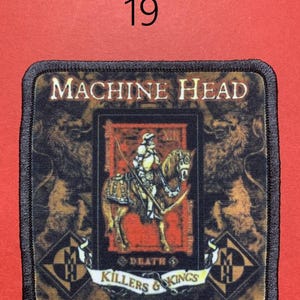 Peut inclure: &Eacute;cusson carr&eacute; avec le texte "MACHINE HEAD" et "KILLERS & KINGS". L'&eacute;cusson pr&eacute;sente un chevalier &agrave; cheval, avec un lion de chaque c&ocirc;t&eacute;. Le num&eacute;ro "19" est au-dessus de l'&eacute;cusson. Bordure noire.