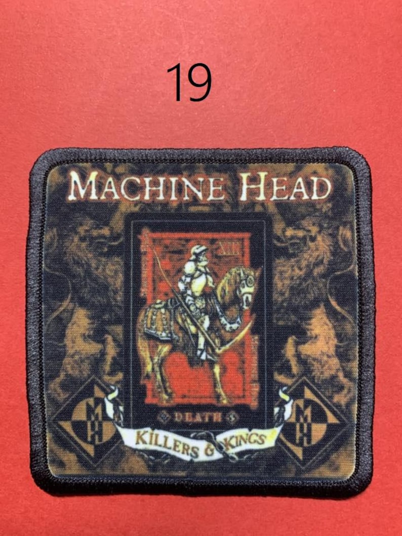 Peut inclure: &Eacute;cusson carr&eacute; avec le texte "MACHINE HEAD" et "KILLERS & KINGS". L'&eacute;cusson pr&eacute;sente un chevalier &agrave; cheval, avec un lion de chaque c&ocirc;t&eacute;. Le num&eacute;ro "19" est au-dessus de l'&eacute;cusson. Bordure noire.