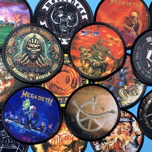 May include: A collection of round, embroidered patches featuring various heavy metal band logos and album art. The patches display vibrant colors and detailed illustrations, including the bands Iron Maiden, Megadeth, and Motörhead.