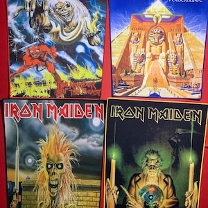 Puede incluir: Cuatro parches de Iron Maiden con ilustraciones vibrantes. Uno presenta una figura esquelética con pelo puntiagudo, otro representa una pirámide con jeroglíficos, y dos más muestran la mascota de la banda, Eddie. Los parches están sobre un fondo rojo.