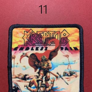 Peut inclure: &Eacute;cusson carr&eacute; &agrave; bordure noire repr&eacute;sentant une sc&egrave;ne de guerrier avec le texte "KREATOR ENDLESS PAIN". L'&eacute;cusson a un fond rouge avec le num&eacute;ro "11" en haut au centre.