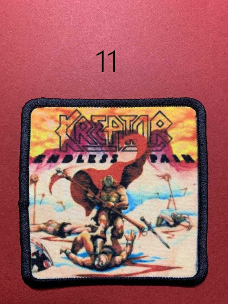 Peut inclure: &Eacute;cusson carr&eacute; &agrave; bordure noire repr&eacute;sentant une sc&egrave;ne de guerrier avec le texte "KREATOR ENDLESS PAIN". L'&eacute;cusson a un fond rouge avec le num&eacute;ro "11" en haut au centre.