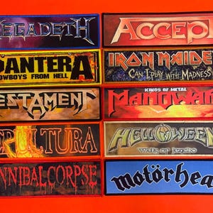 May include: A collection of ten rectangular embroidered patches featuring heavy metal band logos and text including Megadeth, Accept, Pantera Cowboys From Hell, Iron Maiden Can I Play With Madness, Testament, Manowar Kings Of Metal, Sepultura, Helloween Walls Of Jericho, Cannibal Corpse, and Motörhead.