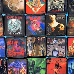 Puede incluir: Una colección de parches cuadrados con portadas de álbumes de varias bandas de heavy metal. Los parches muestran una variedad de colores e imágenes, incluyendo calaveras, figuras y texto. Los parches están dispuestos en un patrón de cuadrícula sobre un fondo azul.