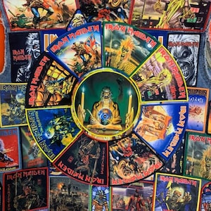 Pode incluir: Um colete jeans coberto com numerosos emblemas do Iron Maiden apresentando várias ilustrações de capas de álbuns. Os emblemas exibem imagens coloridas da mascote da banda, Eddie, em cenas variadas, incluindo batalhas, temas sobrenaturais e imagens de concertos.