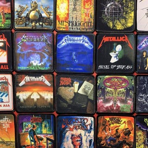 May include: A collection of square patches featuring album art from various heavy metal bands. The patches display vibrant colors and bold graphics, including band logos and album titles. The patches are arranged in a grid pattern.