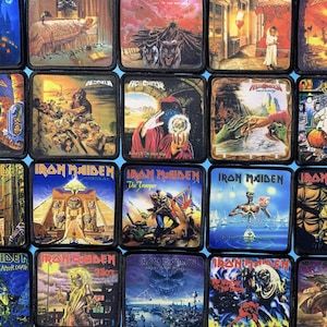 May include: A collection of square patches featuring album art from the band Iron Maiden. The patches display various illustrations in vibrant colors, including fantasy scenes, figures, and the band's logo. The patches are arranged in a grid pattern.