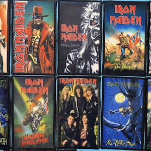 May include: A collection of ten rectangular Iron Maiden embroidered patches featuring various album and single cover artworks, including The Trooper, Fear of the Dark, and Aces High, each with a black border and vibrant, detailed graphic prints.