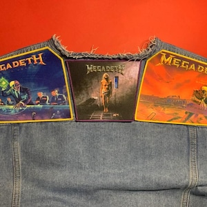 May include: A light blue denim waistcoat featuring three rectangular Megadeth patches sewn across the back. The left patch depicts a boardroom scene, the centre patch shows a figure in a cell, and the right patch displays a post-apocalyptic landscape.