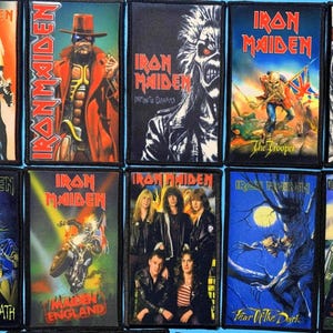 May include: A collection of ten rectangular Iron Maiden embroidered patches featuring various band album art, including The Trooper, Fear of the Dark, and Aces High, each with a black border and vibrant, detailed graphic illustrations.