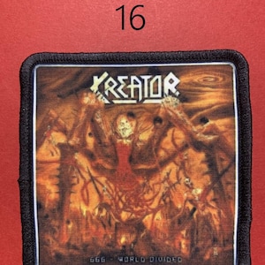Peut inclure: &Eacute;cusson carr&eacute; &agrave; bordure noire avec le nom du groupe "KREATOR" en lettres blanches. L'image repr&eacute;sente une sc&egrave;ne enflamm&eacute;e avec des personnages et le texte "666 - WORLD DIVIDED". Le chiffre "16" est dans le coin sup&eacute;rieur gauche.