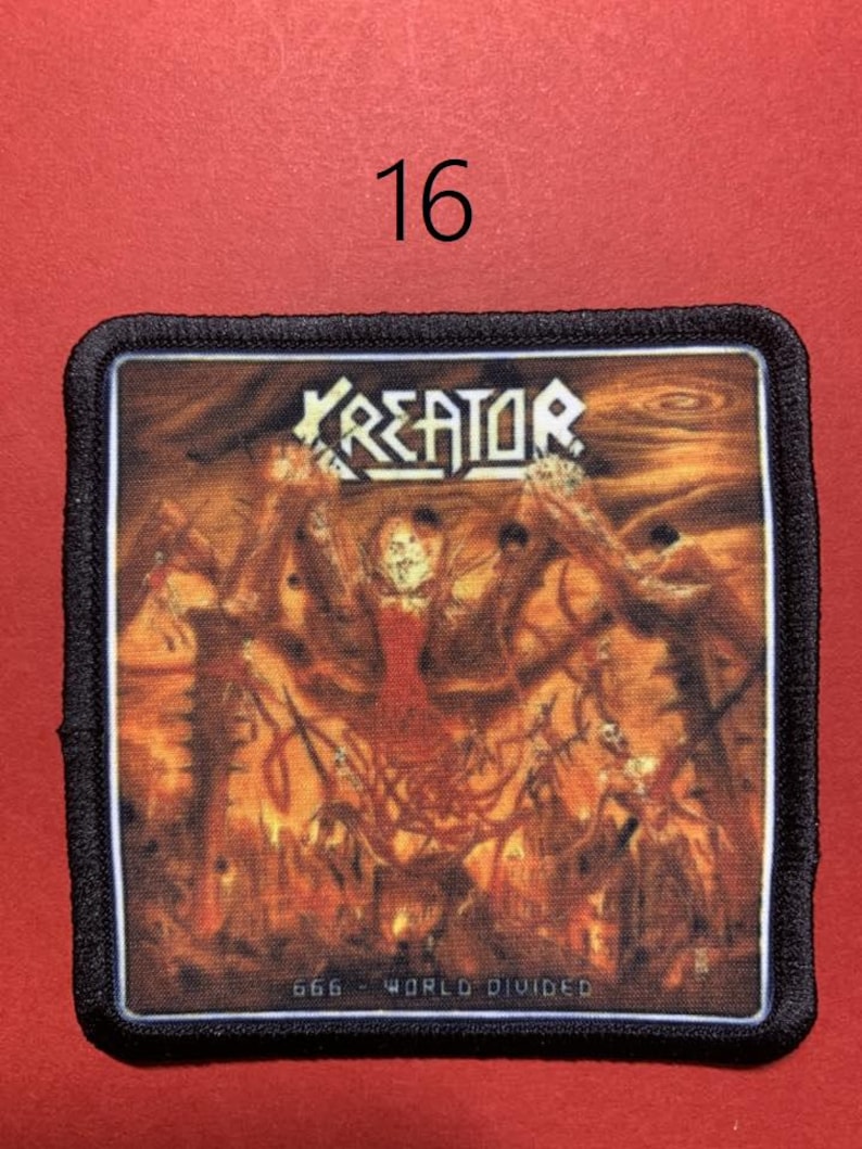 Peut inclure: &Eacute;cusson carr&eacute; &agrave; bordure noire avec le nom du groupe "KREATOR" en lettres blanches. L'image repr&eacute;sente une sc&egrave;ne enflamm&eacute;e avec des personnages et le texte "666 - WORLD DIVIDED". Le chiffre "16" est dans le coin sup&eacute;rieur gauche.