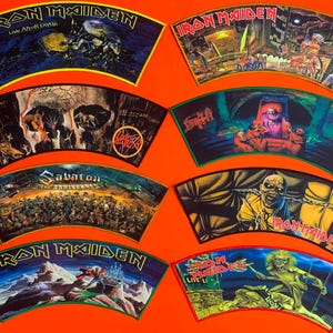 Peut inclure: Huit écussons en tissu en forme d'éventail présentant diverses illustrations de groupes de heavy metal. La collection comprend plusieurs motifs Iron Maiden, un écusson Slayer et un écusson Death. Chaque écusson affiche des graphismes détaillés.