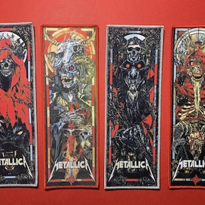 Puede incluir: Cuatro parches rectangulares con ilustraciones góticas de figuras esqueléticas en rojo, negro y blanco. Cada parche tiene el nombre de la banda "METALLICA" en una fuente estilizada en la parte inferior. Los parches están sobre un fondo rojo.