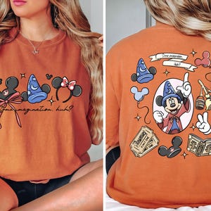 May include: Orange t-shirt featuring Mickey Mouse ears, a wizard hat, and Minnie Mouse ears with a bow. The text "Some imagination, huh?" is written below. The back of the shirt has a Mickey Mouse graphic.