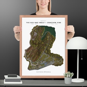 May include: Framed print showing a detailed map of Busch Gardens Williamsburg, with the text "THE BIG BAD WOLF + DRACHEN FIRE" and dates. The map depicts the park's layout, including roller coasters and green areas. The frame is light brown.