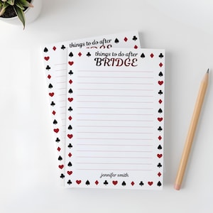 May include: White notepad with red and black playing card suit border. The notepad has the text "things to do after BRIDGE" and lined pages. A wooden pencil rests on the side.