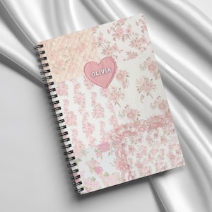 May include: A pink and white floral patterned spiral notebook with a pink heart that says "Olivia" on it.