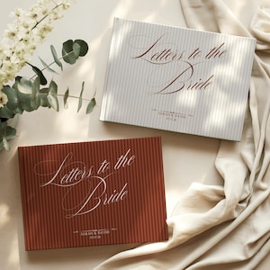 Puede incluir: Dos libros rectangulares con rayas verticales. Un libro es gris claro con texto rojo oscuro que dice "Letters to the Bride" y "Sarah & David 07.17.28". El otro es rojo oscuro con texto blanco que dice "Letters to the Bride" y "Sarah & David 07.17.28".