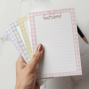 Peut inclure: Un bloc de feuilles rectangulaires avec un motif vichy dans des tons pastel rose, jaune, orange, bleu et violet. La feuille rose supérieure présente une illustration de nœud rose et le texte imprimé from the desk of MRS. SMITH au-dessus des lignes.