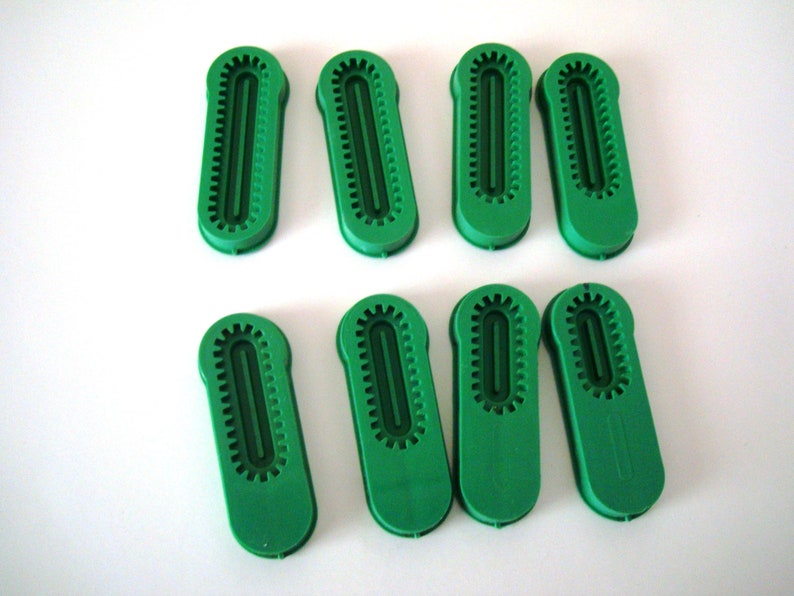 May include: Eight green plastic pieces with a raised design. The pieces are shaped like a long oval with a groove down the center.