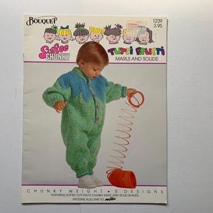 Peut inclure: Une brochure de modèles de tricot avec un enfant portant une combinaison tricotée verte et bleue. La brochure est intitulée "Safice Chunky Tutti Frutti Marls and Solids" et comprend des instructions pour tricoter de la laine épaisse.