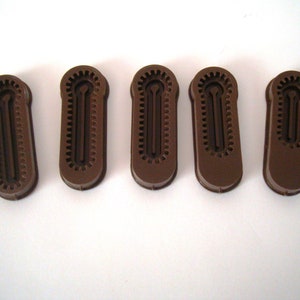May include: Five brown plastic zipper pulls with a textured design. The zipper pulls have a small hole in the center.