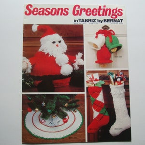 May include: A vintage knitting pattern booklet titled "Seasons Greetings in Tabriz by Bernat". The booklet features illustrations of knitted Christmas ornaments, including a Santa Claus, bells, a tree skirt, and stockings.